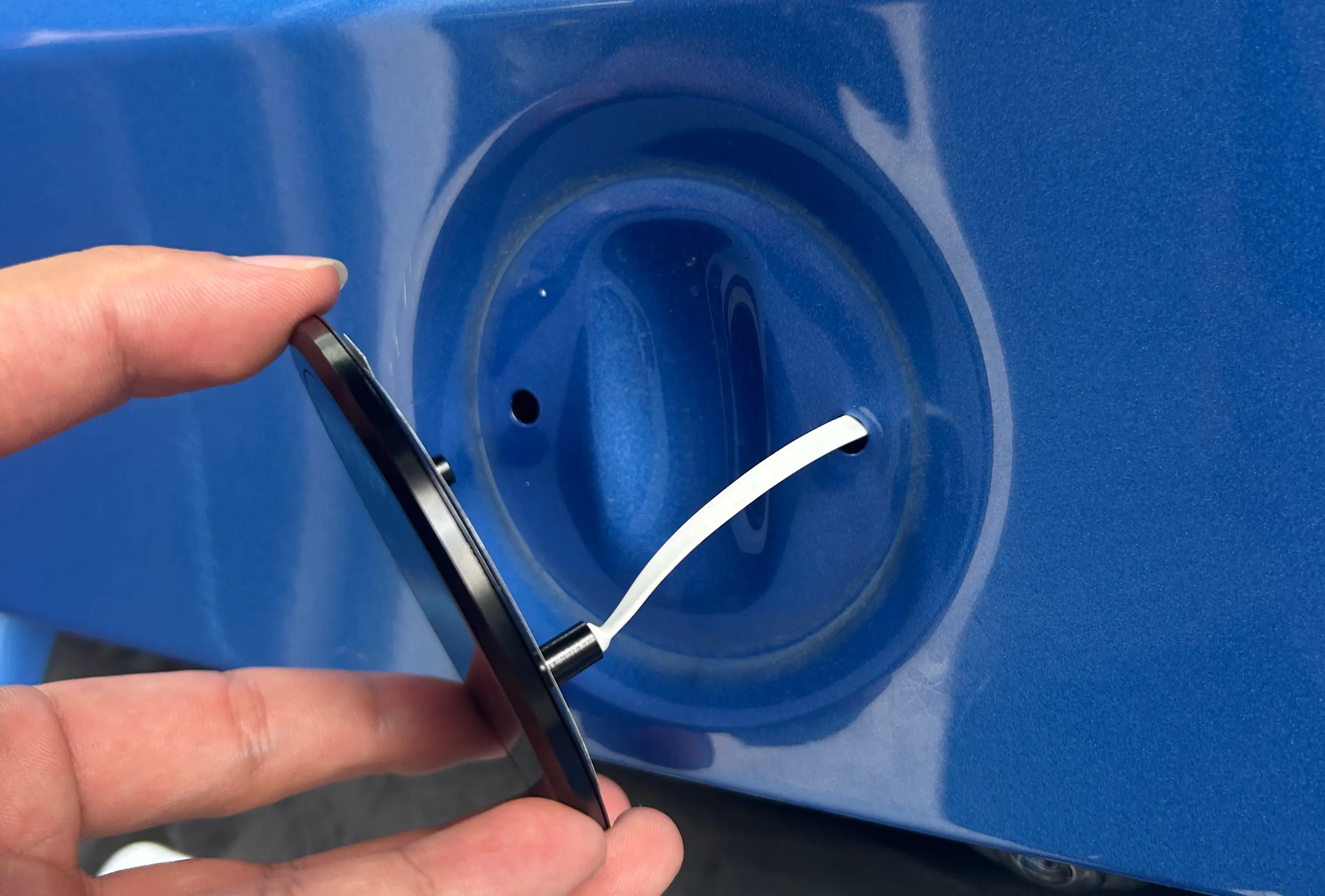 A drill cutting a hole into a car boot lid for an alternative badge