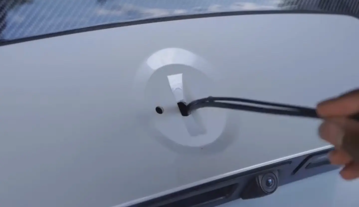 A cable being fed through a freshly drilled hole in a boot lid